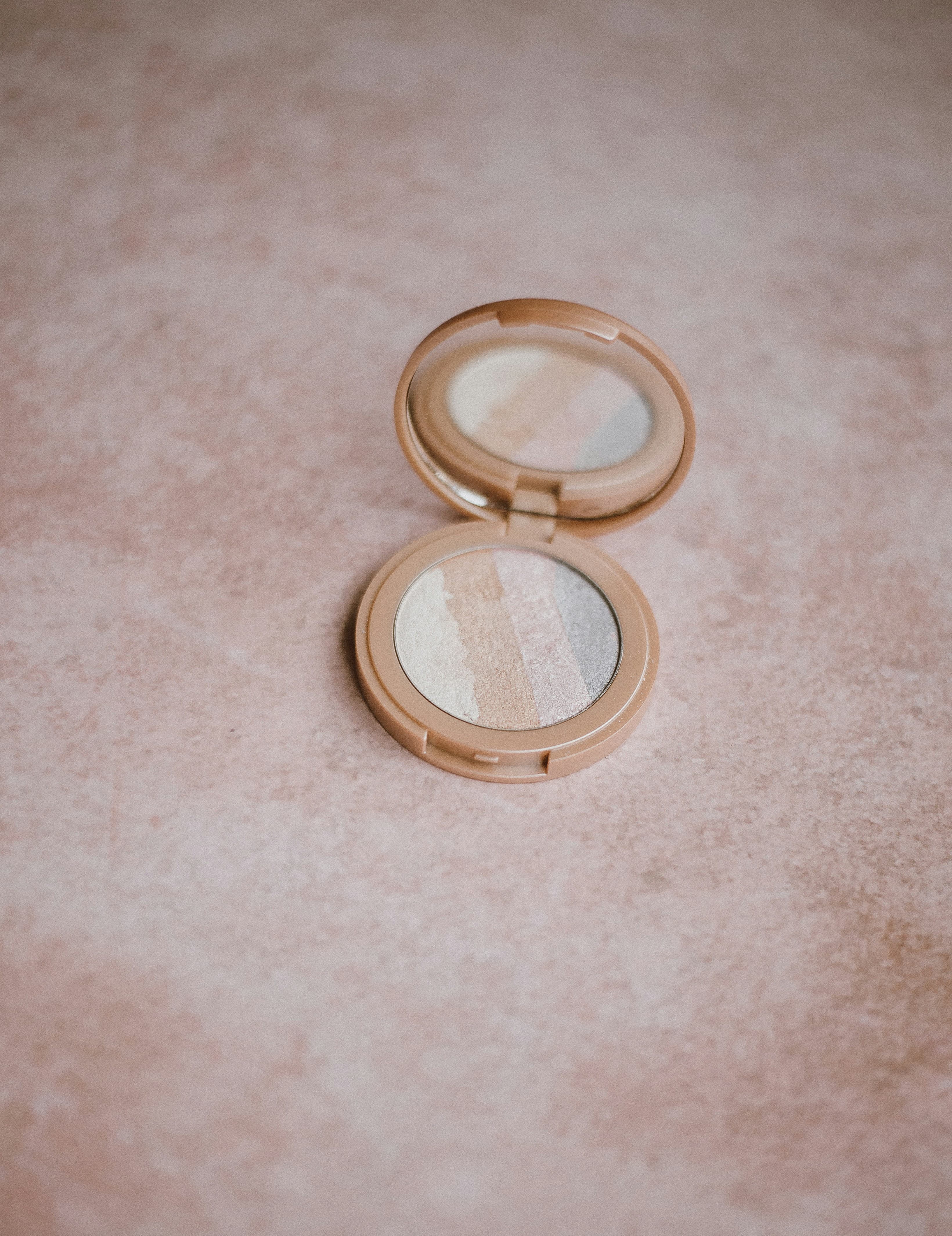 Glass Skin Highlighter in Champagne Veil. Open highlighter compact on a warm surface