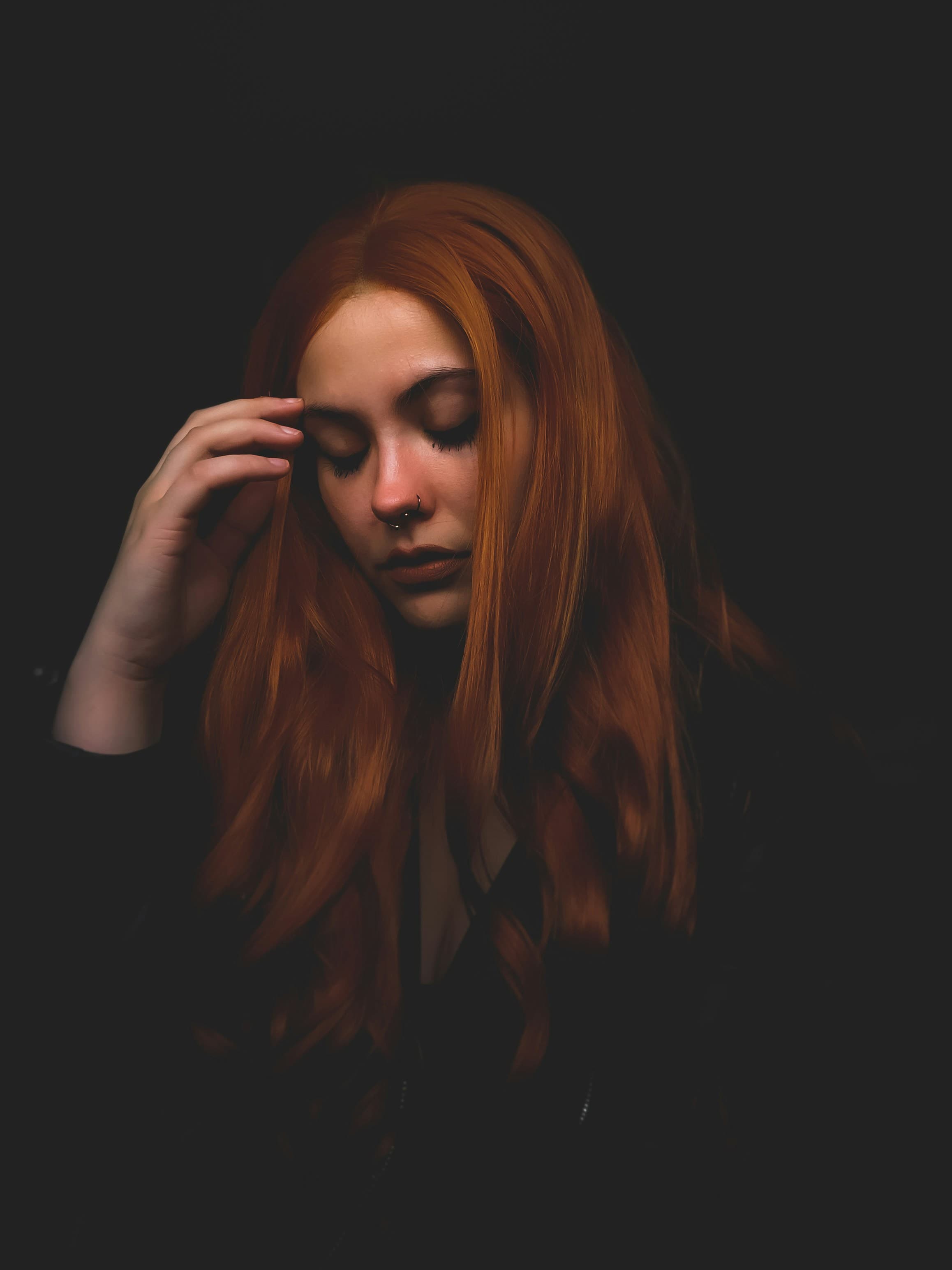 Portrait in low light, hands in red hair